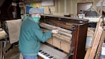 Michael Rohde dissembling a 120-year-old piano to salvage the metal and fine wood for other uses.