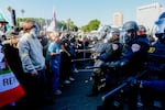 California Highway Patrol officers wearing helmets and visors and carrying what appear to be truncheons face off against civilian protesters on the 101 Freeway in downtown Los Angeles on Sunday. 