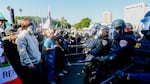 California Highway Patrol officers wearing helmets and visors and carrying what appear to be truncheons face off against civilian protesters on the 101 Freeway in downtown Los Angeles on Sunday.