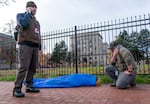 Outreach worker Ryan Hazlett, with Mental Health & Addiction Association of Oregon, and a representative from Recovery Works NW, right, make calls to find treatment options for a man sick from fentanyl, center, in downtown Portland, Ore. on Dec. 13, 2023. The work was part of a pilot program by Portland Police Bureau’s bike squad and addiction recovery providers that launched in December 2023. 