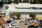 Police vehicles and ambulances in a parking lot outside a large building.