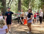 Courageous Kids camp counselor Dan Campbell and his younger sister lead a rendition of the camp song, “Sticky Moose.” The Campbells were campers here after the death of their mom.