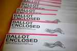 A stack of envelopes is printed with the words "Ballot enclosed" on each.
