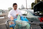 A person loads their car with a donation from a food bank.