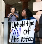 Robin Ye, left, and Candace Avalos take the stage at Portland City Hall to protest City Council's proposal to overhaul voter-approved changes to charter reform on July 18, 2023. Ye was a part of the Charter Review Commission tasked with suggesting changes to the city charter.