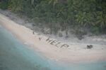 Three men stranded on an uninhabited Pacific island signaled for help using palm fronds on the beach.