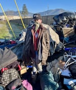 Rachel Beeman, who had been living at the now-closed camp site since it opened last summer in Grants Pass, Ore., keeps watch over her and some neighbors' belongings piled up outside the fenced area.