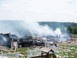 Two firefighters stand on the debris around the smoldering wreckage of the the three houses that exploded near Rustic Ridge Drive and Brookside Drive in Plum, Pa., on Saturday.