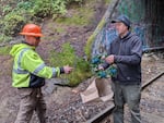 Bruce Shoemaker, a founder of the Black Butte Center for Railroad Culture, hands over the wreath to a railroad worker to be hung over Tunnel 13. Hanging a wreath has become a common tradition every year.