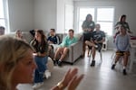 At Next Steps, Cody attends the morning meeting where he and other participants share what they did over the weekend. The participants are sitting on a sofa and chairs in a room.