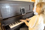 Molly Gilbert plays her family's old player piano at her home in East Portland, Ore., on March 5, 2025. “We had several Christmas rolls. So we’d get down and it would just go through a medley of five or six Christmas songs. And we’d all be singing along,” Gilbert said.