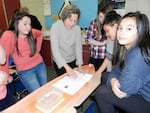 Sunset Middle students work with a volunteer from the Coos Bay Boat Building Center to create graphic for their model.