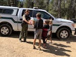 Laura Conard, a deputy with the Deschutes County Sheriff's Office, hands a box of free school meals to Shane, Peyton and Logan Smith (left to right, ages 12, 8 and 7, respectively) outside the Smiths' home near La Pine on Monday, August 31, 2020.