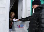 An elderly woman casts a ballot during a presidential election via a mobile election committee, who visit people who cannot physically attend a polling station, in Nikolayevka village outside Siberian city of Omsk, 2236 km (1397 miles) east of Moscow, Russia, on Saturday, March 16, 2024.