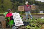 An activist with the environmental action group Extinction Rebellion watches over a protest garden planted near the tracks of Zenith Energy's oil-by-rail terminal in Portland, Oregon, on Sunday, April 21, 2019.