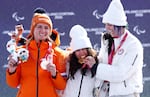 Kate Delson (C) and Brenna Huckaby (R) of Team United States pose for a photo with their flags on the podium during the medal ceremony for the Para Snowboard Women's Banked Slalom SB-LL2.