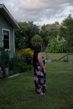 A woman poses for a portrait outside her home, Saturday, July 19, 2025, in Tampa. Her family are discussing emergency plans if she or her husband were to be detained, and are looking to move to another state where the police presence is less felt. (Lexi Parra for NPR)