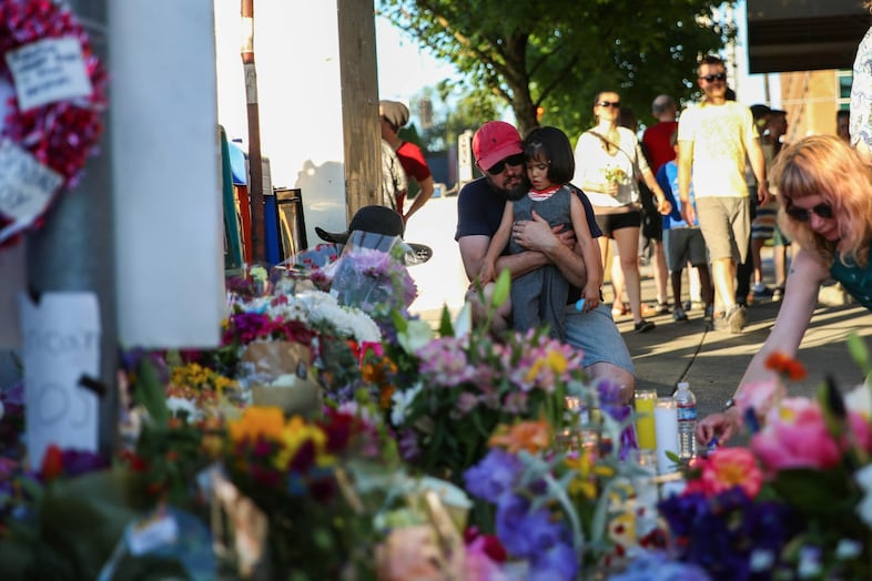 A man hugs his daughter next to one of the memorials.