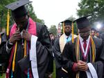 Graduating students at the Morehouse College commencement bow their heads Sunday, May 19, 2024, in Atlanta. President Biden addressed the graduating class of 2024 and warned about "extremist forces" he says threaten the soul of the nation.