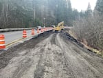 This image provided by the Oregon Dept. of Transportation shows crews working to repair landslide damage on Oregon Route 6 as traffic gets by in one open lane.