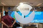 An employee standing with his back to the camera looks at multiple hurricane models displayed on large screens at the National Oceanic and Atmospheric Administration's National Hurricane Center in Miami on May 30, 2025.
