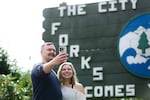 Matthew Miller (left) and Kerigan Fabery (right) take a selfie in front of the sign that welcomes visitors to the city of Forks, Wash. They were among hundreds of visitors who came to town to celebrate the 20th anniversary of the "Twilight" series.