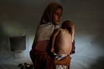 Hidaya, a 31-year-old Palestinian mother, carries her sick 18-month-old son Mohammed al-Mutawaq, who is also displaying signs of malnutrition, inside their tent at the Al-Shati refugee camp, west of Gaza City, on July 24, 2025.