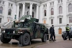 Police walk past armored vehicles outside the Wisconsin state capitol Sunday, Jan. 17, 2021, in Madison, Wis. Security has been increased around the capitol because of concerns that protests leading up to President-elect Joe Biden's inauguration could turn violent and destructive. (AP Photo/Morry Gash)