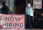 A customer wears a face mask as they carry their order past a now hiring sign at an eatery in Richardson, Texas. 