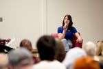 A woman holds a microphone and talks to an audience.