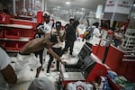 In this Wednesday, May 27, 2020 photo, a looter uses a claw hammer as he tries to break in to a cash register at a Target store in Minneapolis. Rioters ignited fires and looted stores all over the city, as peaceful protests turned increasingly violent in the aftermath of the death of George Floyd.