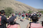 Anibal Rocheta, with his partner Maria Teresa Lopes over his shoulder, translates the finer points of whitewater rafting for the group. Mostly, how not to hit your companions with your paddle. On the banks of the Lower Deschutes River, July 8, 2023.