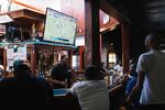 People gather around the bar while watching football.