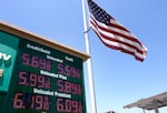 An American flag on a tall flagpole flies above a sign displaying gas prices in red digital numbers at a gas station in Arcadia, California, on May 11.