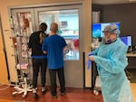 In this August 2021 photo, visitors peer into the room of a COVID-19 patient in the intensive care unit at Salem Hospital in Salem, Ore. At that time the hospitalization rate of unvaccinated COVID-19 patients was squeezing hospital capacity, with several running out of room to take more patients.