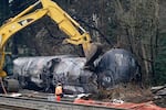 Workers use heavy equipment to begin to move one of several train cars which had been hauling crude oil and derailed days earlier, Tuesday, Dec. 29, 2020, in Custer, Wash. A spokesperson for BNSF Railways said three cars ruptured, spilling an unknown amount of crude oil onto the ground.