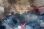 An air tanker drops retardant at a wildfire burns at a hillside in Yucaipa, Calif., Saturday, Sept. 5, 2020. Three fast-spreading wildfires sent people fleeing and trapped campers in one campground as a brutal heat wave pushed temperatures above 100 degrees in many parts of California.