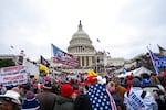 A crowd of hundreds or thousands of people carrying Trump banners and wrapped in US flags surrounds the US Capitol in Washington, D.C.