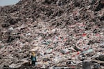 A registered scavenger, who mainly collects plastic waste to sell, walking in a landfill in Indonesia.