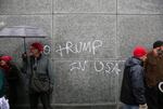 Demonstrators stand near a spray-painted anti-Trump message on the side of downtown Portland building during the Women's March on Portland on Saturday, Jan. 21, 2017.