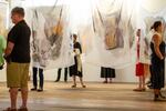 Attendees interact with more than a dozen art pieces printed on silk chiffon fabrics that hang from the ceiling of the Center for Native Arts & Cultures building during the grand opening of the "Matrilineal Memory" solo exhibition by 2023 LIFT artist Mikaela Shafer, Hopi, (Coyote Clan) on May 10, 2024.