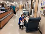 FILE - In this Aug. 20, 2021, file photo, a nurse talks to a patient in the emergency room at Salem Hospital in Salem, Ore., with gurneys lining the hallway behind them, ready to take patients if needed. Gov. Kate Brown announced Wednesday, Aug. 25, 2021, that the state has contracted with a medical staffing company to provide up to 500 health care workers to hospitals around the state to help respond to the surge in patients due to the delta variant.