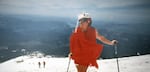 Kathy Phibbs stands on the summit of Mount St Helens in a red chiffon dress and pillbox hat after the mountain reopened to climbers in 1987.