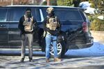 Masked agents stand at an intersection during an ICE immigration enforcement operation in St. Paul, Minn., in January with snow on the ground.