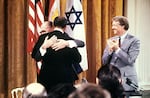 Egyptian President Anwar al-Sadat (back to camera) and Israeli Premier Menachem embrace each other, on Sept. 17, 1978, after signing a peace agreement in the White House with US President Jimmy Carter.