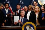 California Gov. Gavin Newsom holds up a signed bill related to redrawing the state’s congressional maps on August 21 in Sacramento.