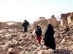 An Afghan woman walks with her children amid debris after a powerful earthquake struck Herat province in western Afghanistan on Sunday, Oct. 15, 2023.