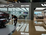 A worker wipes a Rising F7 car model at a floor section selling various Chinese-made electric car brands inside a shopping mall in Beijing, Tuesday, April 4, 2023. (AP Photo/Andy Wong)