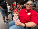 In this photo, Meg Lemaster holds a round white sticker that says "No Data Center" and has a red ring with a slash through it on top of the text. Attending a City Council meeting, she's seated with other opponents of the data center that was proposed for Chesapeake, Virginia.