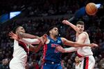 Portland Trail Blazers forward Jabari Walker, left, and Donovan Clingan, right, defend as Detroit Pistons forward Tobias Harris (12) tries to go for the ball during the second half of an NBA basketball game Sunday, March 9, 2025, in Portland, Ore. (AP Photo/Jenny Kane)